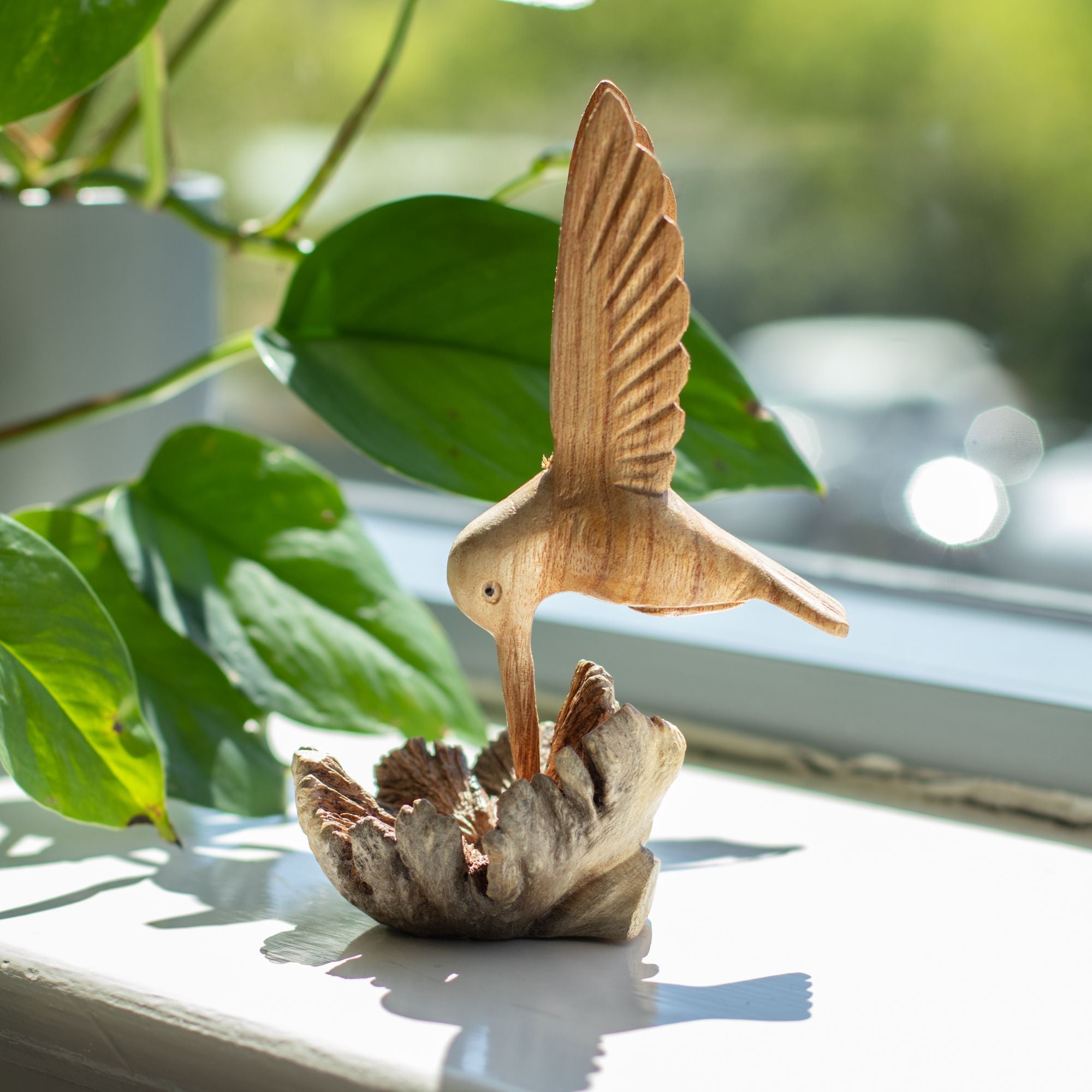 Handgjord skulptur av en kolibri som dricker nektar från trädknöl
