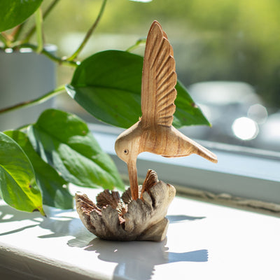 Handgjord skulptur av en kolibri som dricker nektar från trädknöl