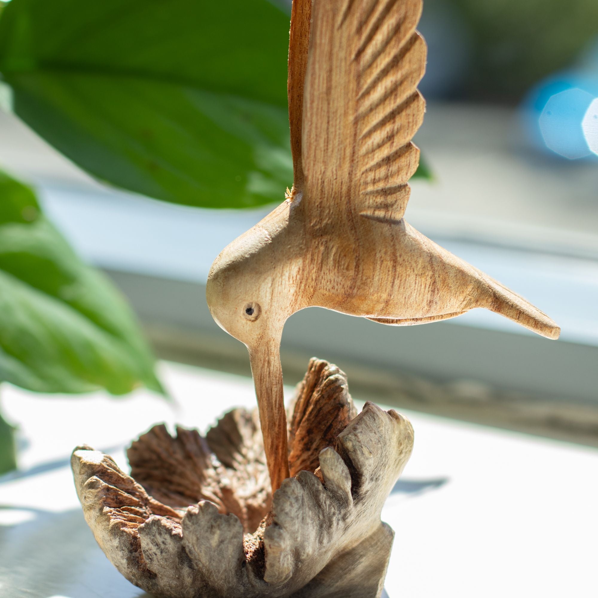 Handgjord skulptur av en kolibri som dricker nektar från trädknöl
